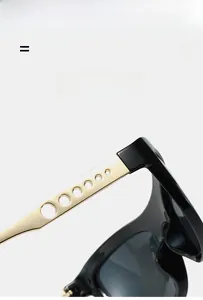 Detail of black cat-eye sunglasses featuring golden hollow-out metal temples with circles