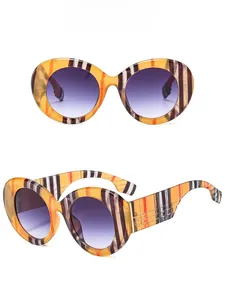 Detail of oversized stripe patterned sunglasses with purple gradient lenses and wide temples