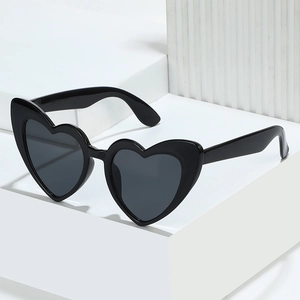 Classic heart-shaped black sunglasses with thick plastic frames on a minimalist podium