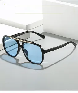 Detail of pilot sunglasses showing black frame, blue lenses and golden metal bridge bar