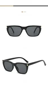 Close-up of black square sunglasses featuring gold metal rivets and grey lenses