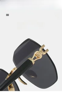 Close-up of golden hollow metal hinge and black temples on rimless sunglasses