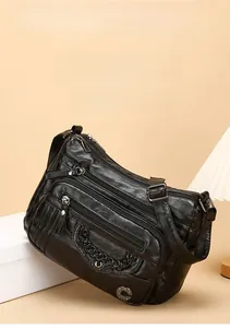 Detail of soft black leather crossbody bag with multiple zippers and woven texture details