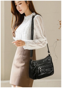 Detail view of black multi-pocket crossbody bag with soft faux leather texture and metal chain