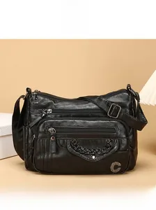 Detail of black pebbled faux leather crossbody bag with multi-zipper pockets and metal logo