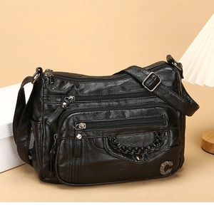 Detail of soft black PU leather texture and multiple zipper pockets on women's crossbody bag