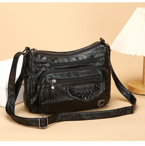 Detail of soft black lychee texture PU leather crossbody bag with multiple zippers and chain