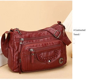 Detail of red leather crossbody bag featuring multiple zippers and woven texture design