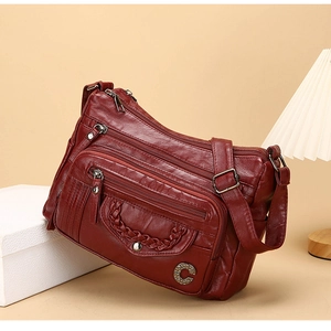 Detail view of burgundy PU leather crossbody bag with multiple zippers and woven texture