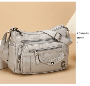 Detail of grey soft leather crossbody bag with multi-zipper layers and woven pocket detail