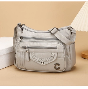 Detail of soft leather crossbody bag featuring multiple zipper pockets and beige texture
