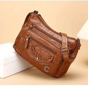 Detailed close-up of brown PU leather crossbody bag with multiple zippers and C-logo