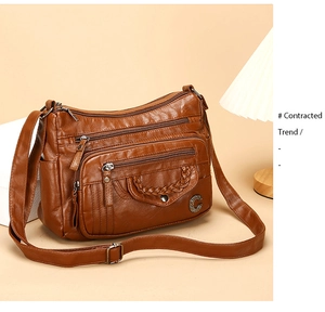 Detail view of brown PU leather crossbody bag featuring metal C-buckle and multiple zippers