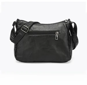 Detail view of the black leather crossbody bag back side showing smooth metal zipper pocket