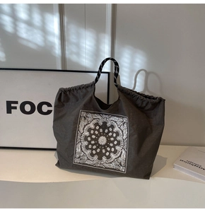 Detail of grey canvas tote bag with white paisley print and striped rope handles