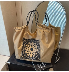 Close-up of khaki tote bag with black bandana paisley pattern and braided handles