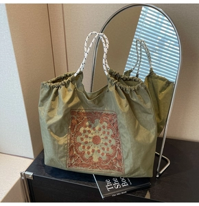Detail of army green canvas tote with brown mandala embroidery and braided rope handles