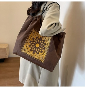 Close-up of brown canvas tote with mandala embroidery and woven strap details