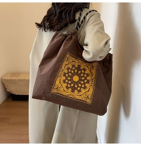 Detail view of brown canvas tote with paisley embroidery and woven rope shoulder strap