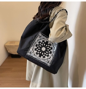 Detailed view of black paisley canvas tote bag with drawstring and rope handles on model