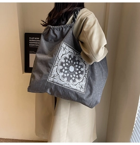 Detail of dark grey drawstring tote bag with white paisley mandala and woven straps