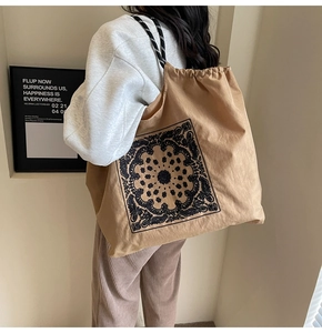 Detail of khaki tote bag with black paisley print and braided drawstring shoulder straps