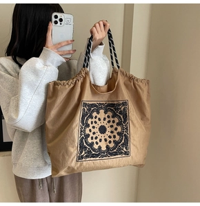 Detail of khaki tote bag with black paisley pattern and braided drawstring handles