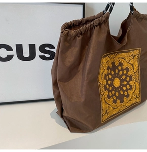 Detail of dark brown canvas tote bag with yellow mandala embroidery and rope handles