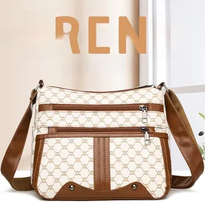 Detail view of multi-zipper shoulder bag with brown patterned texture and metallic studs