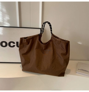 Detail view of brown drawstring tote bag with woven handles and minimalist design