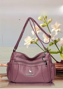 Detail of deep purple pebble leather crossbody bag showing functional zippers and strap