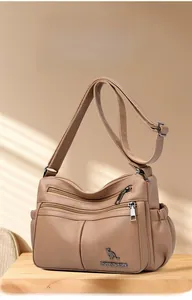 Detail of light brown leather crossbody bag with multiple zippers and side pockets