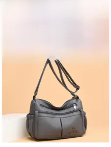 Detail view of grey multi-zipper leather crossbody bag with logo and textured finish