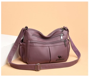 Macro detail of dark purple pebbled leather multi-pocket crossbody bag with kangaroo logo