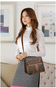 Detail of a large brown patchwork crossbody bag with multi-layer zippers and geometric pattern
