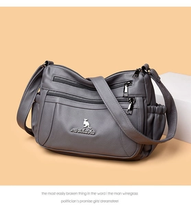 Detail of grey lychee leather crossbody bag featuring multiple zippers and kangaroo metal logo
