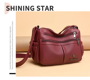 Detail view of burgundy soft leather crossbody bag with multiple zipper compartments and logo