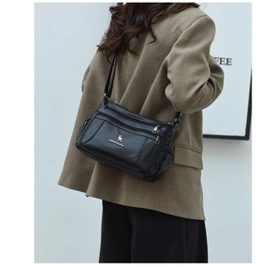 Detailed side view of black lychee grain crossbody bag worn by model with multiple zippers