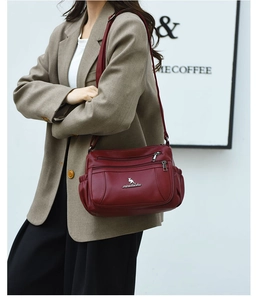 Detail of wine red multi-pocket leather crossbody bag with multiple zippers and logo