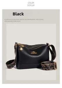 Detail of black pebbled leather bag with triple zippers and woven jacquard strap