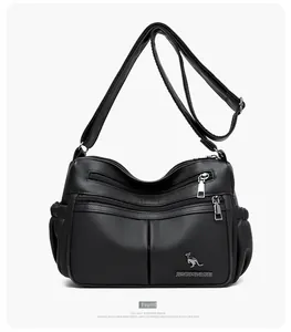 Detail of black pebbled leather crossbody bag showing multi-zipper layers and wide strap
