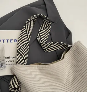 Detail of light beige corduroy tote bag featuring a black and white woven wide strap