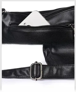 Detail of black pebbled leather crossbody bag with back zipper pocket and adjustable strap