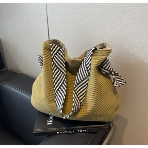 Detail of olive green corduroy tote bag with textured fabric and wide striped shoulder strap