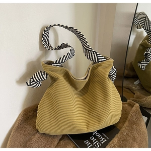 Detail of mustard yellow corduroy tote bag with black and white striped knotted straps