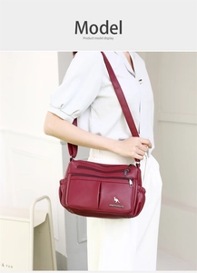 Detail of burgundy textured leather crossbody bag with multiple zippers shown on model