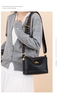 Detail of black pebbled leather crossbody bag with golden zipper and geometric wide strap