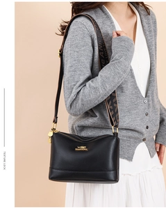 Detail showing pebbled black leather shoulder bag with wide letter-patterned strap