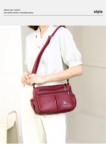 Detail of burgundy textured leather crossbody bag with multiple zip pockets and kangaroo logo