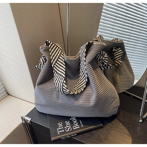 Detail of grey corduroy tote bag showing striped texture and black white strap design